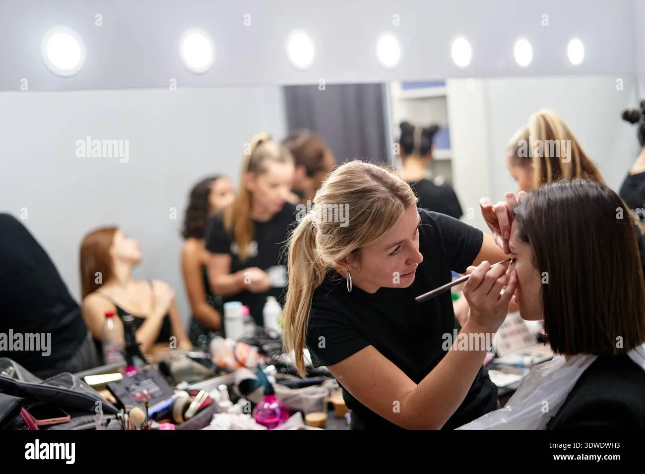 a-makeup-artist-applies-makeup-to-a-model-in-a-well-lit-studio-other-models-are-visible-in-the-background-getting-ready-creating-a-lively-and-energe-3dwdwh3 Đội ngũ makeup chuyên nghiệp giúp bạn tự tin tỏa sáng trong từng khung hình